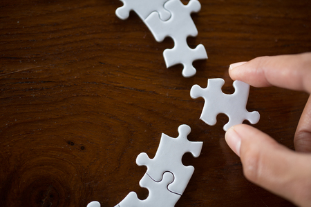 Hand put the last piece of jigsaw puzzle to complete the mission, Business solutions, success and strategy conceptの写真素材