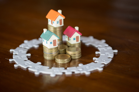 Three house model on stack coins.Jigsaw puzzle, Saving money and property Management concept, investment property, home insurance, savings plan for housing.の写真素材