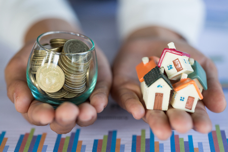 Investor show hand holding a model home and coin , Saving money for buy a new house and loan for plan business investment for real estate in the future concept.の写真素材