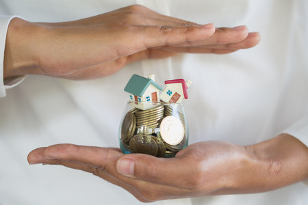 Hand protection, house model on top of stack of money as growth of mortgage credit, Concept of property management. Invesment and Risk Management.の写真素材