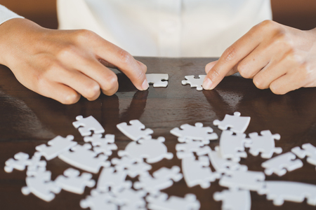 Closeup hand of connecting jigsaw puzzle to complete the mission with sunlight effect, Business solutions, success and strategy conceptの写真素材