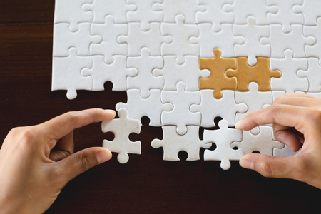 Closeup hand of connecting jigsaw puzzle to complete the mission with sunlight effect, Business solutions, success and strategy conceptの写真素材