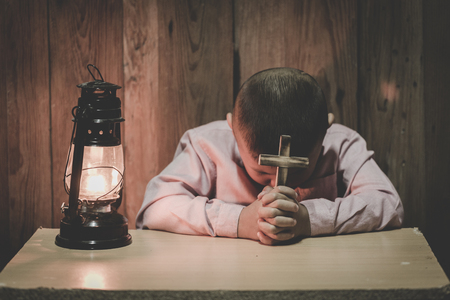 Boy hands holding a holy cross and praying to God, Child Praying for God Religion.の写真素材