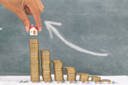 Woman hand hold a  home model put on the stack coin with growing, Savings money for buy house and loan to business investment for real estate concept. Invesment and Risk Management.の写真素材