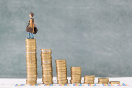 Miniature business people stand on pile of money coin, Travel saving and planing concept.の写真素材