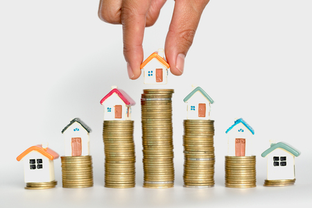 Woman hand hold a  home model put on the stack coin with growing, Savings money for buy house and loan to business investment for real estate concept. Invesment and Risk Management, isolated.の写真素材