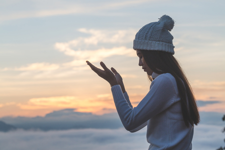 Young christian woman  hands open palm up worship and praying to god  at sunrise, Christian Religion concept background.の写真素材