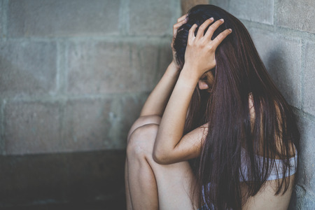 Depressed teenager sitting holding head in hands, stressed sad young woman having mental problems, Abusive and rape, Domestic Violence and Traffickingの写真素材