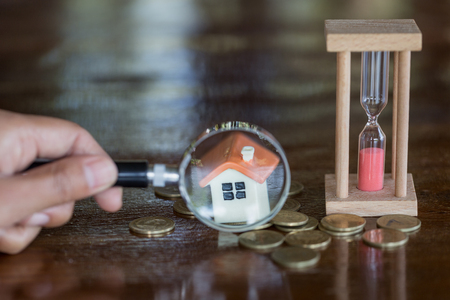 Hand hold a magnifying glass searching for a new home, Loan for real estate or save money for buy a house to family in the future concept.の写真素材