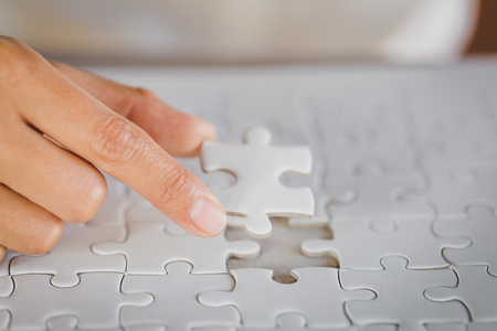 Hand put the last piece of jigsaw puzzle to complete the missionの写真素材