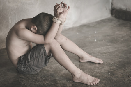 Victim boy with hands tied up with rope in emotional stress and pain,  kidnapped, abused, hostage,  afraid, restricted, trapped, pitiable,  struggle,  Stop violence against children and trafficking Concept.の写真素材