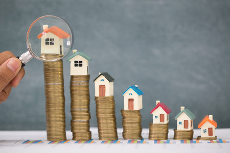 Stack coin and bar graph with grow,  Hand hold a magnifying glass searching for a new home, Loan for real estate or save money for buy a house to family in the future concept.の写真素材