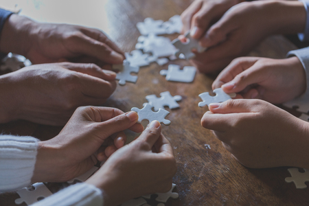 Hands of diverse people assembling jigsaw puzzle, Youth team put pieces together searching for right match, help support in teamwork to find common solution concept, top close up viewの写真素材