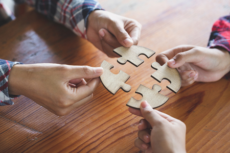Hands of diverse people assembling jigsaw puzzle, team put pieces together searching for right match, help support in teamwork to find common solution concept, top close up viewの写真素材