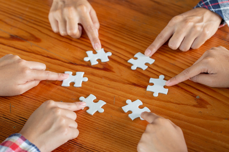 Hands of diverse people assembling jigsaw puzzle, team put pieces together searching for right match, help support in teamwork to find common solution concept, top close up viewの写真素材