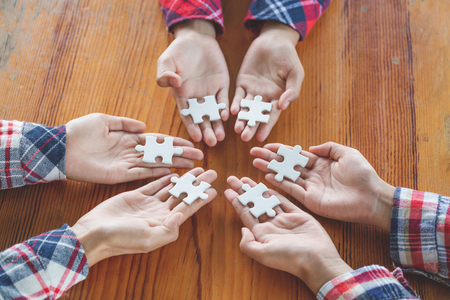 Hands of diverse people assembling jigsaw puzzle, Youth team put pieces together searching for right match, help support in teamwork to find common solution concept, top close up viewの写真素材