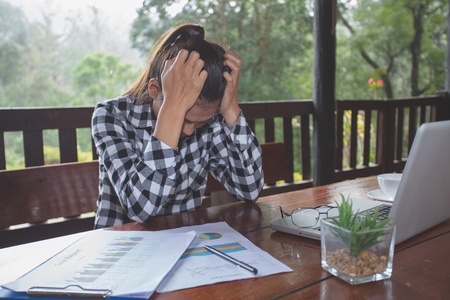 Business Woman Having Headache While Working Using Laptop Computer. Stressed And Depressed Girl Touching Her Head, Feeling Pain While Sitting At Wooden Tabl, Work Failure Conceptの写真素材