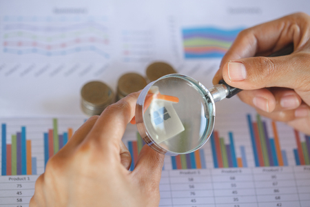 Hand hold a magnifying glass searching for a new home, Loan for real estate or save money for buy a house to family in the future concept.の写真素材