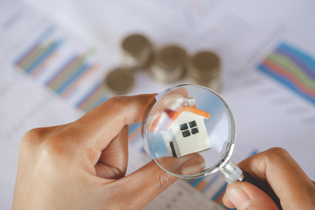 Close-up Of A Businessperson's Hand Looking At House Model Through Magnifying Glass, House searching concept with a magnifying glassの写真素材