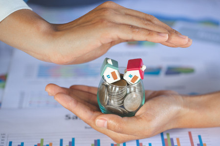 Hand protection, house model on top of stack of money as growth of mortgage credit, Concept of property management. Invesment and Risk Management.の写真素材