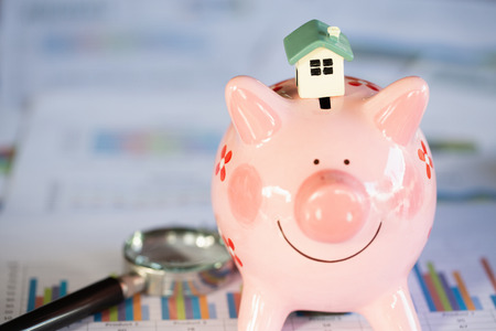 A house model placed on a piggy bank, finance and banking,  Saving money and property Management concept.の写真素材