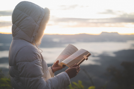 Woman with  cross and bible in hands praying for blessing from god  in the morning, spirituality and religionの写真素材