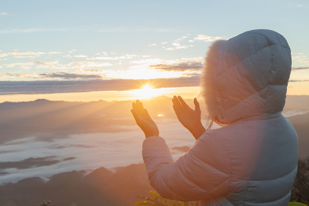 Christian woman  hands praying to god on the mountain background with morning sunrise. Woman Pray for god blessing to wishing have a better life. Christian life crisis prayer to god.の写真素材