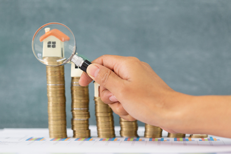 Close-up Of A Businessperson's Hand Looking At House Model Through Magnifying Glass, House searching concept with a magnifying glassの写真素材