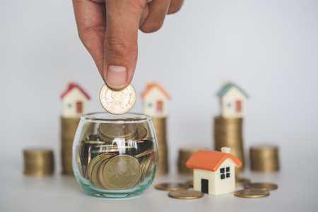 Hand putting money coin stack ,  buy a house,Risk,  Indicates the growth of home and finance, planning savings money of coins to buy a home concept property mortgage and investment for a house.の写真素材