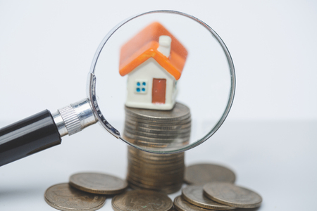 Model house on stack coin ,  magnifying glass searching for a new home, House searching concept with a magnifying glassの写真素材