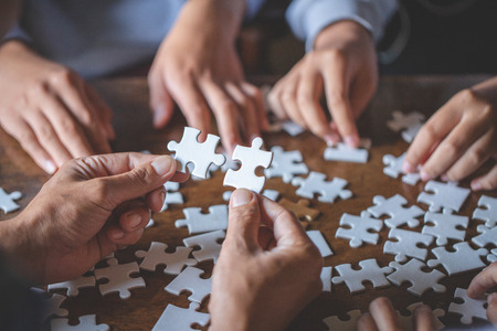 Hands of diverse people assembling jigsaw puzzle, team put pieces together searching for right match, help support in teamwork to find common solution concept, top close up viewの写真素材