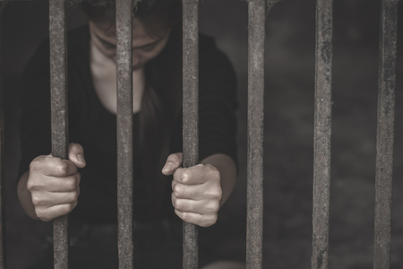 Close up hand of woman prisoner holding old iron bar in jail. Imprisonment, Women violence and abused concept,  human trafficking Concept, international women's day.の写真素材