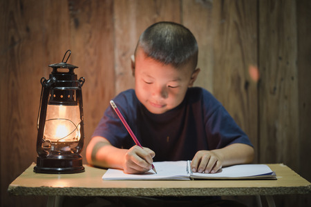 Poor children write books illuminating with oil lamps, Disadvantaged Children doing homework, Education Concept.の写真素材