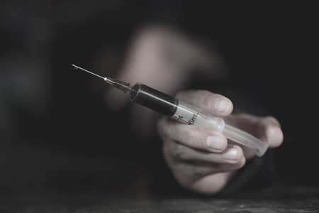 Young woman  hand holding a syringe and drug overdose,The concept of crime and drug addiction. 26 June, International Day Against Drug abuse.の写真素材