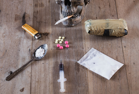 Drugs of various kinds and human skulls on the wooden table, Collection of different hard drugs Heroin, Pills, Tobacco,The concept of death from drugsの写真素材