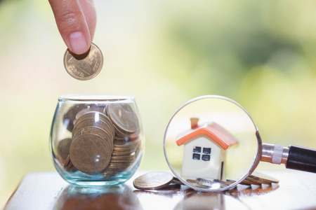  planning savings money of coins to buy a home concept, mortgage and real estate investment.  saving or investment for a house, a model of a house and a magnifying glassの写真素材