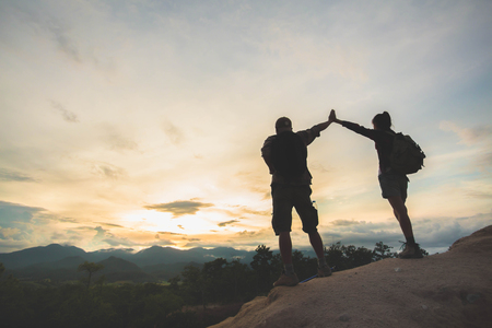 Silhouette of hikers standing on top of hill and enjoying sunrise over the valley, family, Couples, male and female, standing on top of the mountain.の写真素材