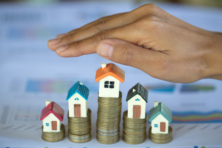 Hand protection, house model on top of stack of money as growth of mortgage credit, Concept of property management. Invesment and Risk Management.の写真素材