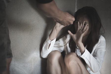 Woman covering her face in fear of domestic violence, Violent young man threatening his girlfriend, Stop violence and abuse women Concept.の写真素材