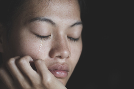 Sad depressed woman suffering and from family life. women sitting in dark room and crying, Young beautiful women thinking how to solve problem, Stop violence against womenの写真素材
