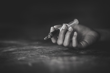 Woman hand of a drug addict and a syringe with narcotic syringe lying on the floor, Overdose, drug concept.の写真素材