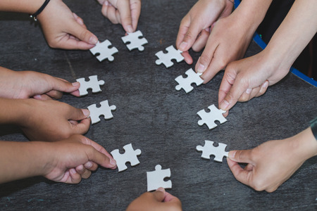 Hands of diverse people assembling jigsaw puzzle, Youth team put pieces together searching for right match, help support in teamwork to find common solution concept, top close up viewの写真素材