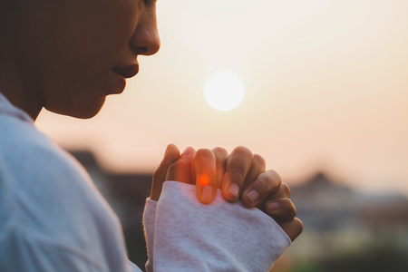 Woman praying in the morning on the sunrise background. Christianity concept. Pray background. Faith...