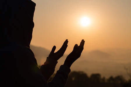 Silhouette of young  human hands open palm up worship and praying to god  at sunrise, Christian Religion concept background.の写真素材