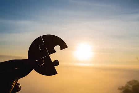 Silhouette of business woman hand holding  jigsaw puzzle piece against sunrise, Business solutions,...
