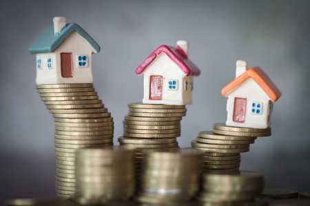 Mini house on stack of coins, Concept of Investment property, Investment risk and uncertainty in the real estate housing market.の写真素材