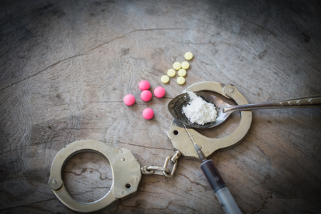 Drug syringe and cooked heroin on spoon and handcuffs . Concept - punishment for possession of narcotic drugs.の写真素材