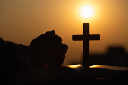 Silhouette of young woman praying with crosses and bibles at sunrise, Christian Religion concept background.の写真素材