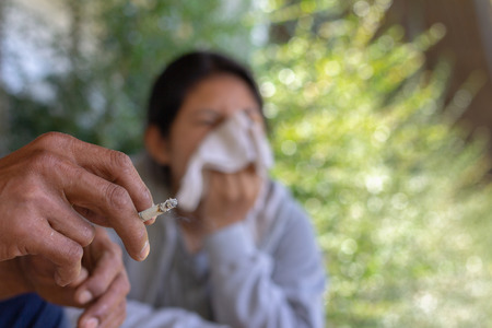 Passive smoking concept. Man is smoking cigarette and woman is covering her face. Concepts stop...