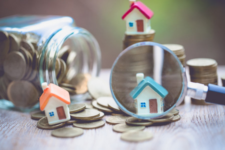 concept of a mortgage, a coin, a model of a house and a magnifying glass, house and money. magnifying glass and coins, construction, rental housing.の写真素材